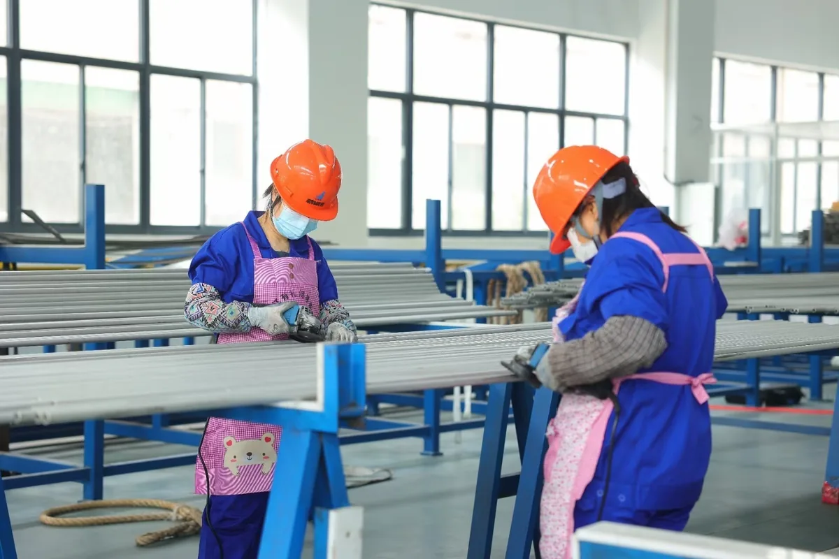 Operators carrying out manual tube finishing in the workshop